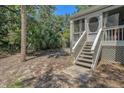 Backyard with tropical foliage and stairway leading up to a screened-in porch with decorative entrance at 433 Double Eagle Trace, Seabrook Island, SC 29455