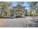 Charming home with a welcoming front porch, double garages, and a gravel driveway surrounded by mature trees at 6021 Jibe Ct, Awendaw, SC 29429