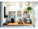 Efficient kitchenette featuring butcher block counters, white brick walls, and open shelving at 1125 Rifle Range Rd, Mount Pleasant, SC 29464