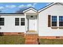 Close-up of the charming white-sided house entrance with a brick porch, windows, and decorative shutters at 1409 Main St, Bonneau, SC 29431