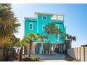 Bright turquoise beach house featuring palm trees, ground-level parking, and inviting coastal charm at 1699 E Ashley Ave # B, Folly Beach, SC 29439