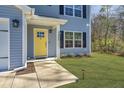 Close-up of the inviting yellow front door with glass accents, side lights, and manicured landscaping at 3405 Painswick Rd, Johns Island, SC 29455