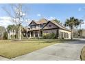This home features a manicured lawn, side-entry three-car garage, American flag, and a blend of stone and stucco at 4162 Club Course Dr, North Charleston, SC 29420