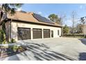 View of the home's three-car garage with dark brown doors, solar panels, and a smooth, sealed concrete surface at 4162 Club Course Dr, North Charleston, SC 29420