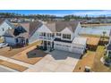 Aerial view of a two-story home with a porch and three-car garage near a serene lake at 624 Sienna Way, Summerville, SC 29486