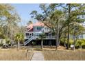 A picturesque view of a two-story home with a red roof and spacious decks, nestled among lush greenery at 1464 Dupree Creek Rd, Awendaw, SC 29429