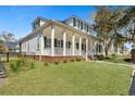 Charming home with a large porch, white columns, black shutters, and a lush green lawn at 2028 Ironstone Aly, Charleston, SC 29407