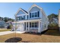 Beautifully landscaped corner lot with a light blue two-story home with a welcoming front porch at 221 Waning Way, Charleston, SC 29492
