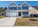 Two-story home with light blue siding and dark shutters, featuring a welcoming front porch at 221 Waning Way, Charleston, SC 29492