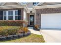 Close up of the brick facade home with two-car garage, green grass and landscaping at 316 Knawl Road, Moncks Corner, SC 29461
