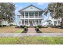 Inviting two-story home featuring a spacious double-decker porch, manicured lawn, and charming curb appeal at 4070 Egret Perch Ct, Ravenel, SC 29470