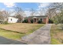 Charming single-story brick home with a long driveway and a well-manicured lawn, all under a blue sky at 4203 Marilyn Dr, North Charleston, SC 29418