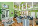 Bright living room featuring high ceilings, a fireplace, and an open floor plan leading to the kitchen and natural light at 944 Hammocks Way, Edisto Island, SC 29438