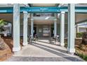 Building 6 entryway, featuring four white pillars, metal chairs, small tables, elevator, and palm trees at 134 Marsh View Villas, Folly Beach, SC 29439