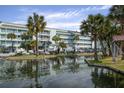 An exterior view of multi-level condo building with boat parking, dock, and grassy area adjacent to a body of water at 134 Marsh View Villas, Folly Beach, SC 29439