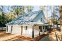 Side view of a modern home with metal roof, a covered porch, and natural light filtering through surrounding trees at 143 Harvest Way, Walterboro, SC 29488