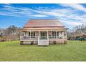 Charming historic home with a large front porch, featuring a vibrant green lawn and mature trees at 242 Weathers Farm Rd, Bowman, SC 29018