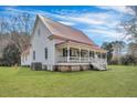 Spacious lawn surrounds an historic home, featuring a covered front porch, red metal roof and painted white siding at 242 Weathers Farm Rd, Bowman, SC 29018