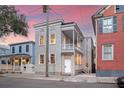 Classic home showcasing double porches, neutral siding, and a welcoming facade in a vibrant urban setting at 40 Pitt St, Charleston, SC 29401