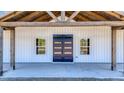 Inviting front porch with exposed wood beams, a modern front door, and views of the surrounding landscape at 709 Oakridge View Trl, Ridgeville, SC 29472