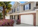 Two-story townhome featuring a single-car garage, black shutters and a blooming azalea bush at 8741 Grassy Oak Trl, North Charleston, SC 29420