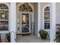 Inviting front porch with arched windows, columns, potted plants, and stylish decor at 9394 Harroway Rd, Summerville, SC 29485