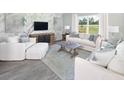 Bright living room with white couches, light blue accents, herringbone accent wall, and plenty of sunlight at 115 Royal Cainhoy Way, Huger, SC 29450