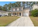 Two-story home with neutral siding, black shutters, covered front porch, and attached garage at 215 Trickle Dr, Summerville, SC 29483