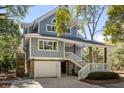 Exterior view of a beautiful home with a garage and inviting covered porch with stairs and white railing at 2202 Oyster Catcher Ct, Seabrook Island, SC 29455