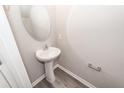 Small powder room featuring a pedestal sink, an oval mirror, a towel rack, and wood-look flooring at 522 Truman Dr, Goose Creek, SC 29445