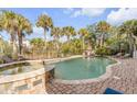 Gorgeous backyard pool and jacuzzi surrounded by an inviting brick patio and lush tropical landscaping at 65 Ocean Point Dr, Isle of Palms, SC 29451