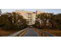 Condo exterior framed by lush trees, accessible by private wooden walkway at 108 Fairbanks Oak Aly # 302, Daniel Island, SC 29492