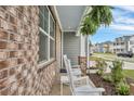 Inviting brick-accented porch with rocking chairs, lush ferns, and views of a quiet residential street at 109 Loon Dr, Summerville, SC 29483