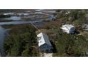 Aerial view of a modern house with a light gray roof surrounded by water and lush greenery at 2101 Guerins Bridge Rd, Wando, SC 29492