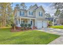 Charming two-story home with a inviting front porch, a well-kept lawn, a driveway and an attached two car garage at 401 Waring St, Summerville, SC 29483