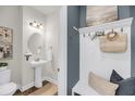 Stylish powder room featuring a sleek pedestal sink, oval mirror, and a lovely beachside decor at 524 Amalie Farms Dr, Charleston, SC 29492