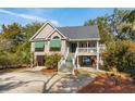 Inviting stilt home featuring a covered front porch and lush landscaping at 601 Foredeck Ln, Edisto Island, SC 29438