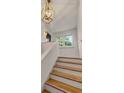 Bright stairway featuring hardwood steps, white risers, and a statement light fixture at 7 Logan St # F, Charleston, SC 29401