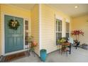 Inviting front porch with a blue door, decorative wreath, plants, and a bench, creating a cozy outdoor space at 7503 Hawks Cir, Hanahan, SC 29410