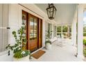 Welcoming front porch features a lantern, potted plants, rocking chairs, and a wood-paneled front door at 1010 Tall Pine Rd, Mount Pleasant, SC 29464