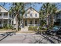 Two-story home with palm trees and a neatly manicured yard, features a welcoming front porch and inviting appeal at 102 Barnaby St, Charleston, SC 29492