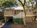 Two-story home with covered parking and front stairs, embraced by lush mature trees at 1121 Summer Wind Ln, Seabrook Island, SC 29455