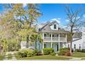 Beautiful home showcasing a double porch, complemented by mature trees and landscaping at 1300 Carol Oaks Dr, Mount Pleasant, SC 29466