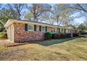 Brick home with dark shutters, surrounded by lush greenery and mature trees at 1929 Westminster Rd, Charleston, SC 29407