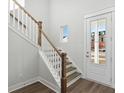 Bright foyer with white and wooden staircase, wood floors, and view of the front door at 217 Denham St, Summerville, SC 29486