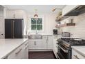 Bright kitchen features subway tile, stone counters, a farmhouse sink, open shelves and stainless steel appliances at 29 27Th Ave, Isle of Palms, SC 29451