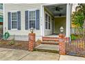Inviting front porch with brick steps, lantern detail, black iron fence and ceiling fans at 312 White Gables Dr, Summerville, SC 29483