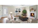 Bright living room featuring a cozy fireplace, large window, hardwood flooring, and neutral-toned furniture at 319 Bluebell Ave, Summerville, SC 29483