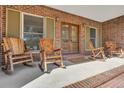 Inviting brick front porch featuring rustic wooden rocking chairs, creating a cozy and relaxing outdoor space at 732 Lindhaven Dr, Pineville, SC 29468