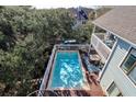 Beautiful in-ground pool surrounded by a deck, tall trees, and a white fence on this lovely property at 8 Fairway Oaks Ln, Isle of Palms, SC 29451